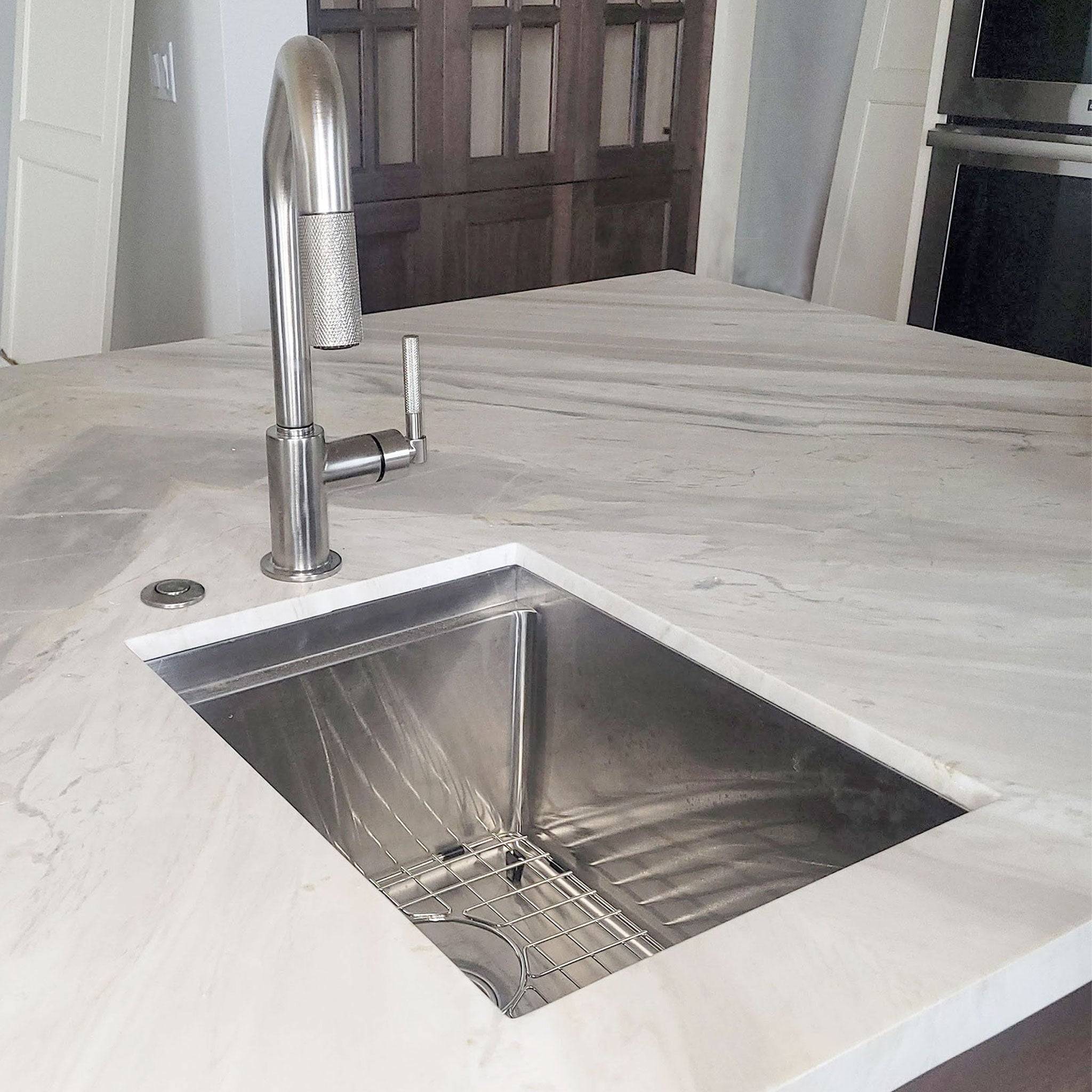 Undermount 15-inch stainless steel workstation bar sink installed in a marble countertop. A sleek and modern addition to any kitchen.