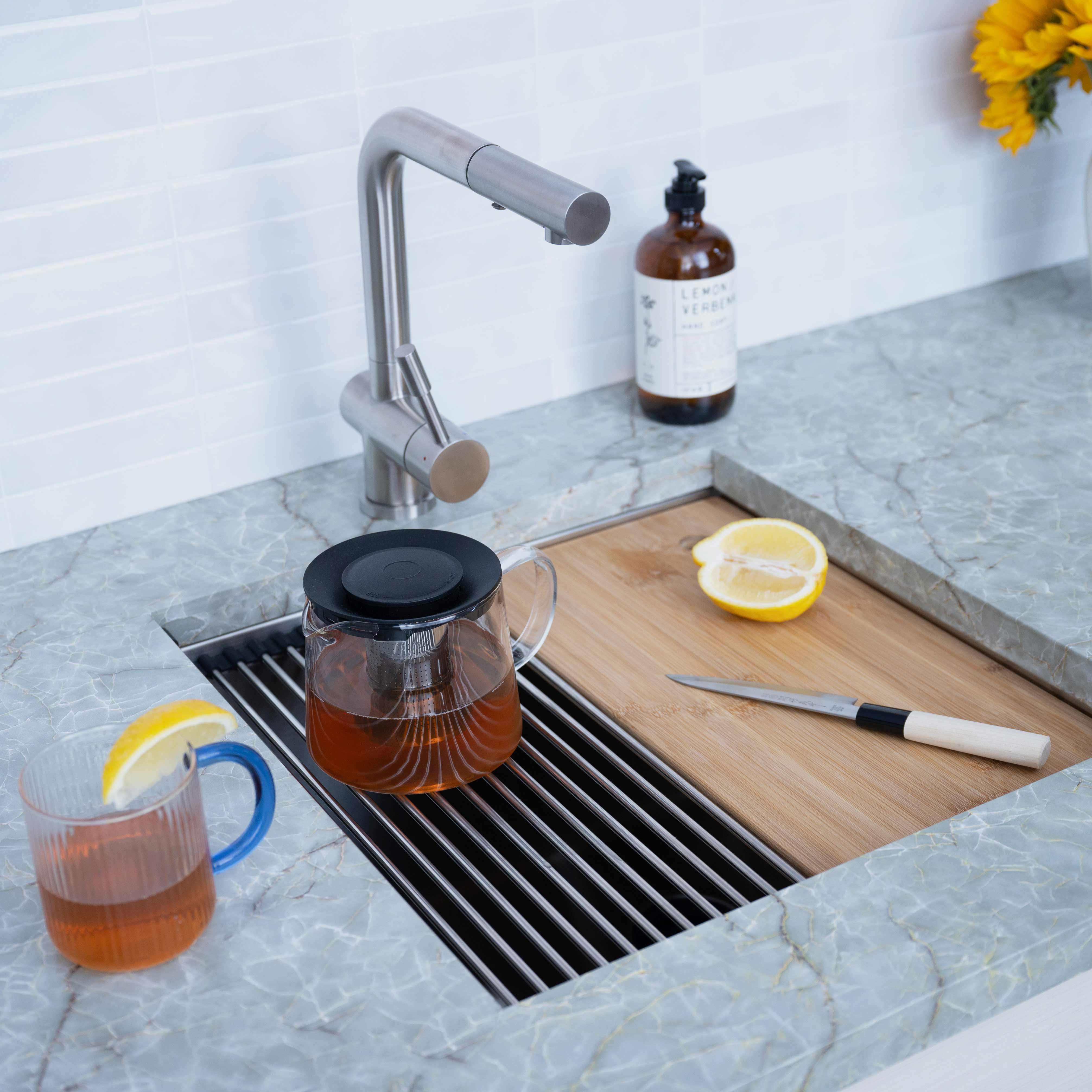 19-inch stainless steel workstation sink installed in a kitchen with accessories. Features a roll-up drying rack and bamboo cutting board.