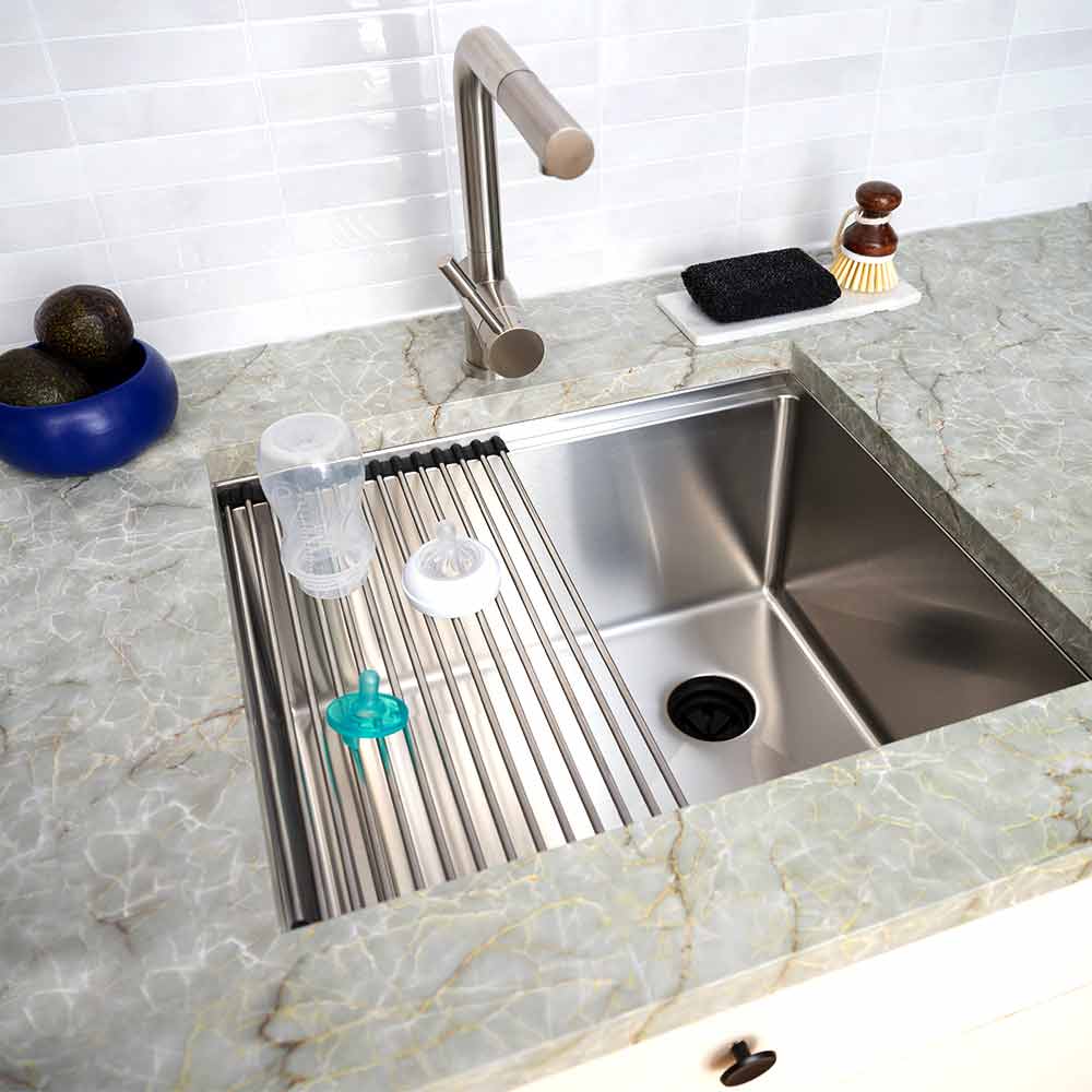 22-inch stainless steel workstation sink installed in a kitchen with a roll-up drying rack. Ideal for food prep and bar areas.
