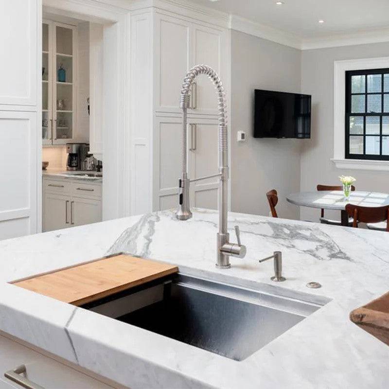 Modern kitchen with a 31-inch stainless steel workstation sink seamlessly integrated into a marble countertop, featuring a built-in ledge for accessories.