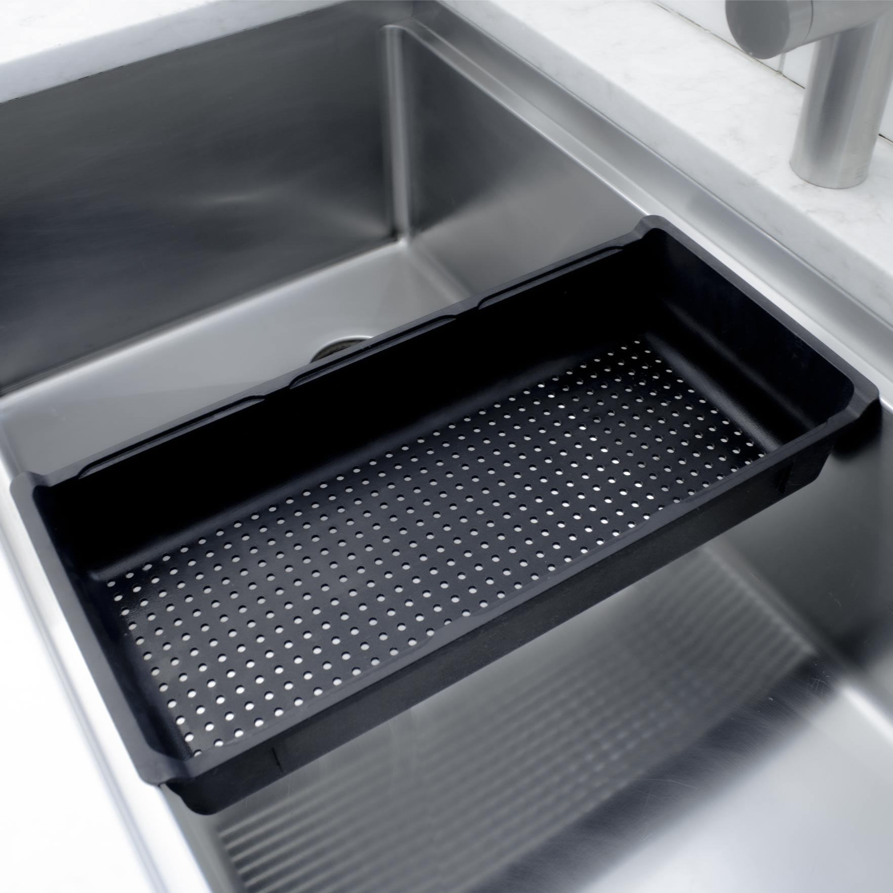 Black rinsing tray inside of a modern kitchen sink