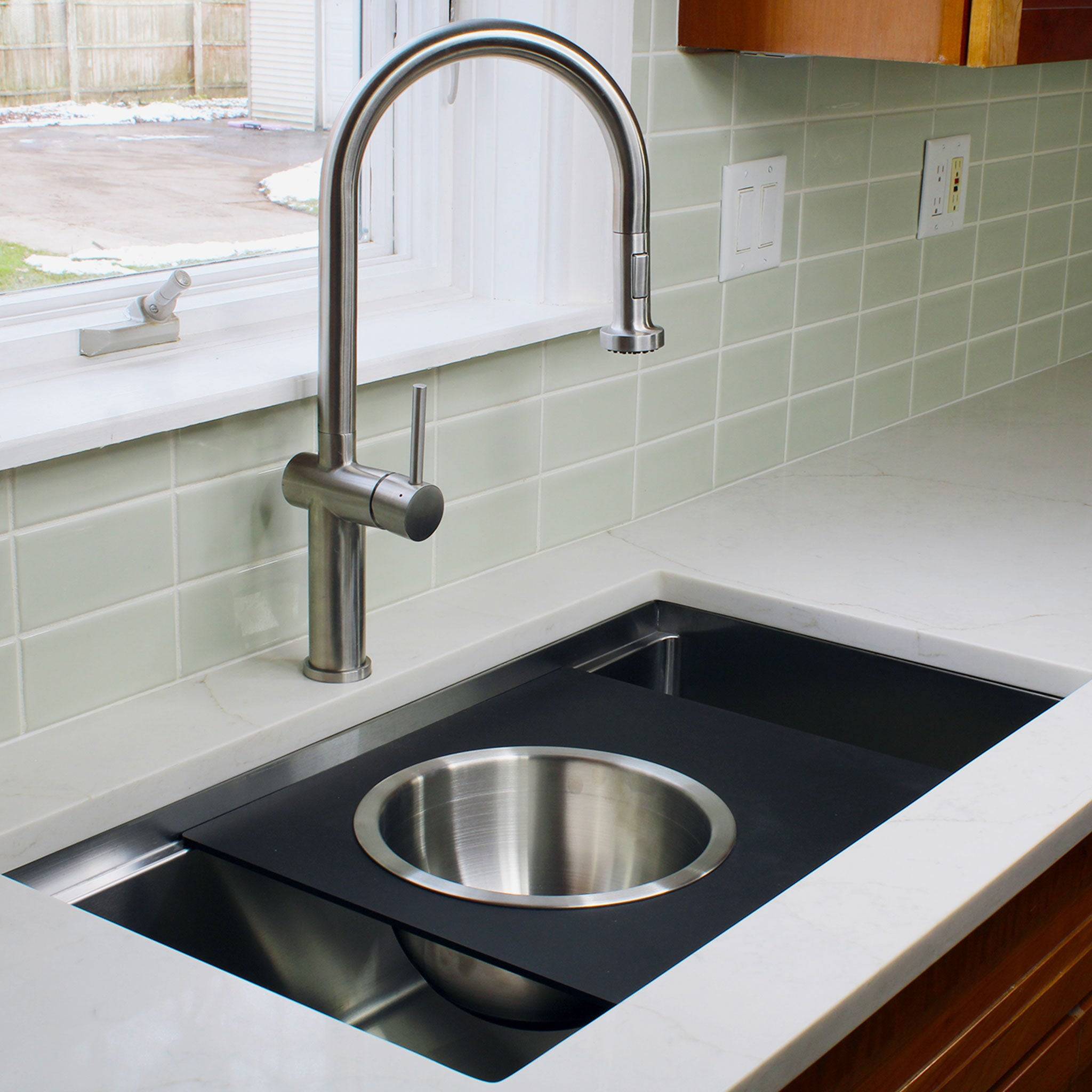 Modern kitchen featuring an 18-inch black cutting board with a stainless steel mixing bowl, designed for workstation sinks.