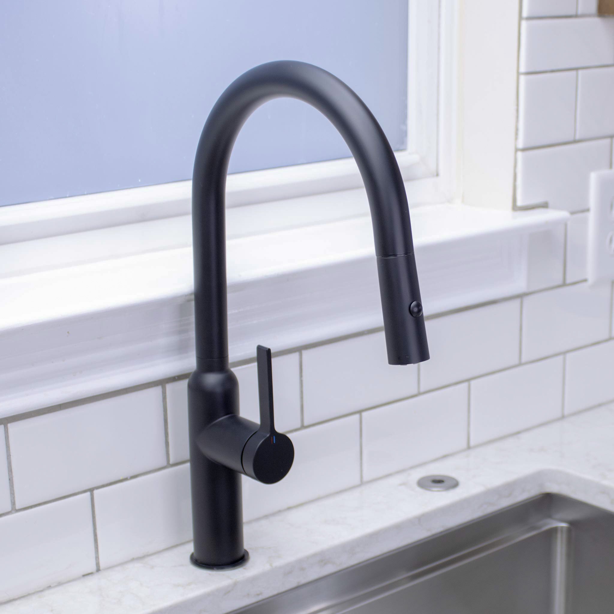 Matte black stainless steel Claudette Kitchen Faucet streaming water into Workstation Sink