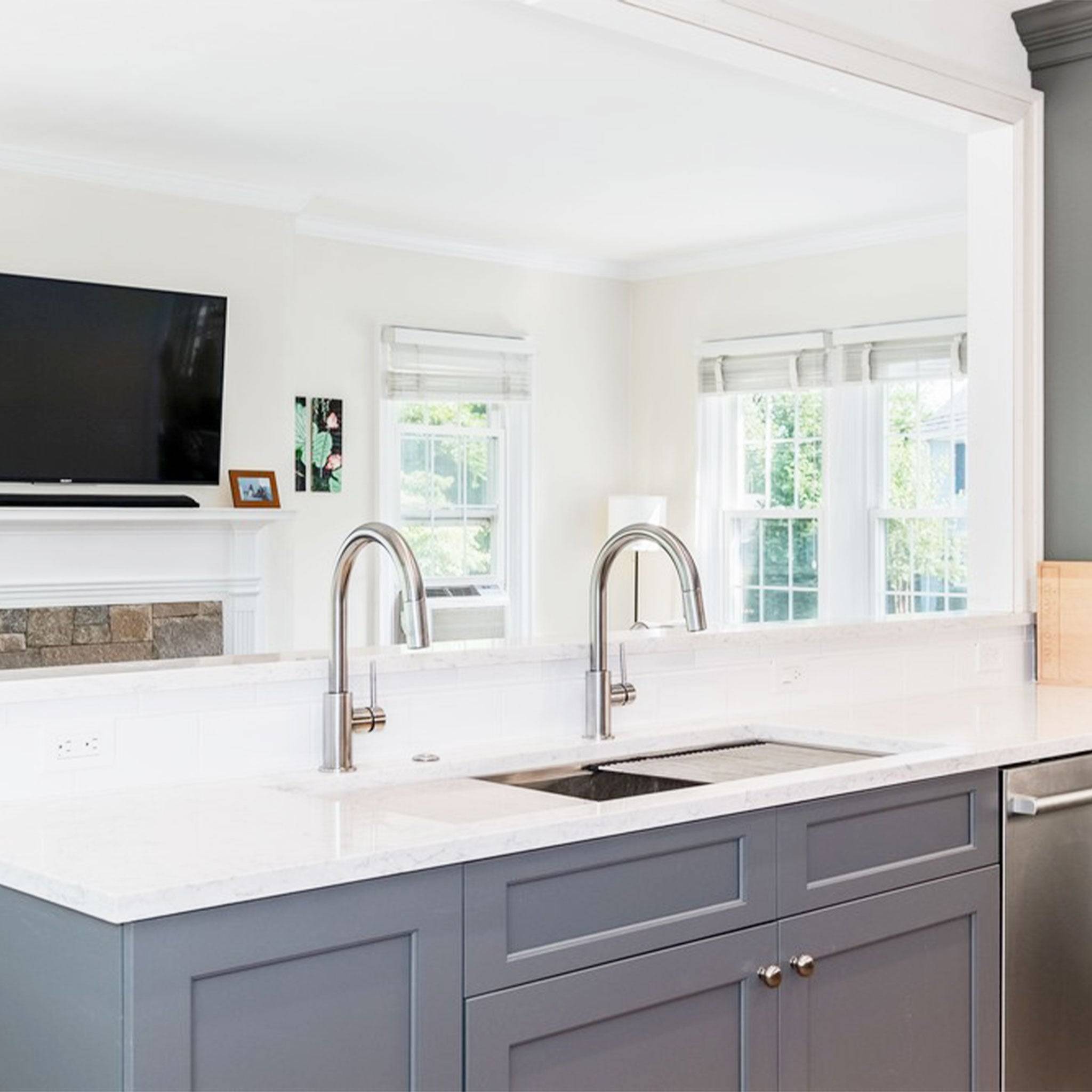 Elegant kitchen with a 46-inch double bowl workstation sink installed in a white marble countertop, complemented by dual high-arc faucets.