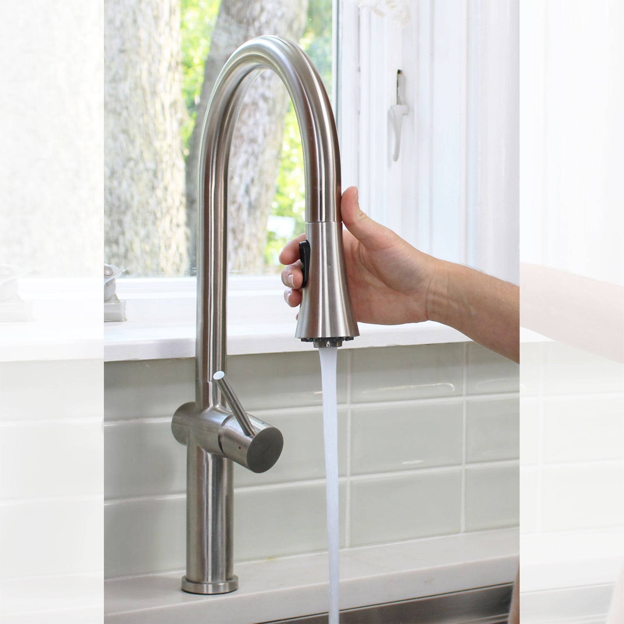 Hand pulling down the Bella stainless steel kitchen faucet’s spray head, showcasing its flexible and ergonomic design for easy rinsing.