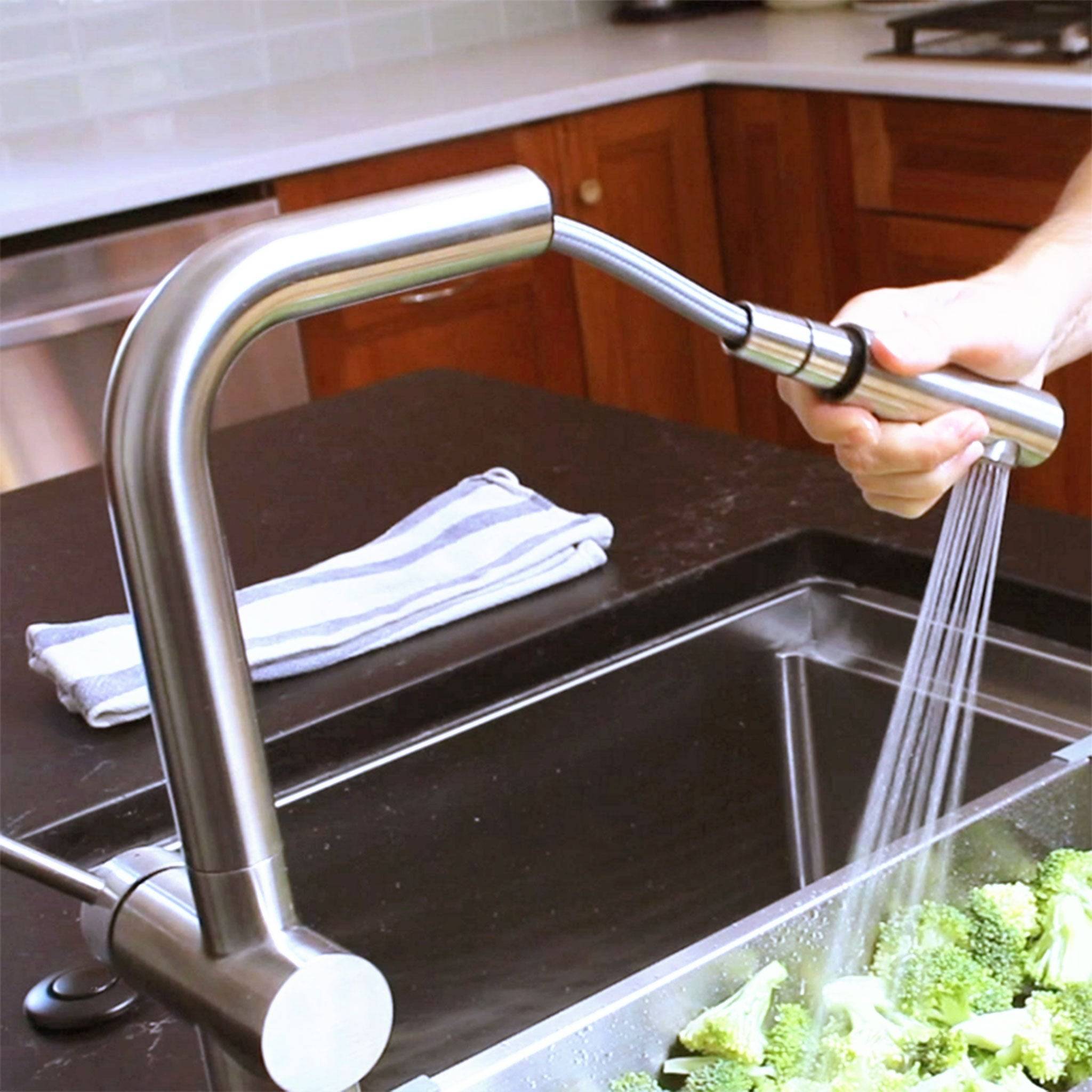 Ardell Stainless Steel Kitchen Faucet with a pull-out spout spraying water, demonstrating its functionality for easy cleaning and rinsing.