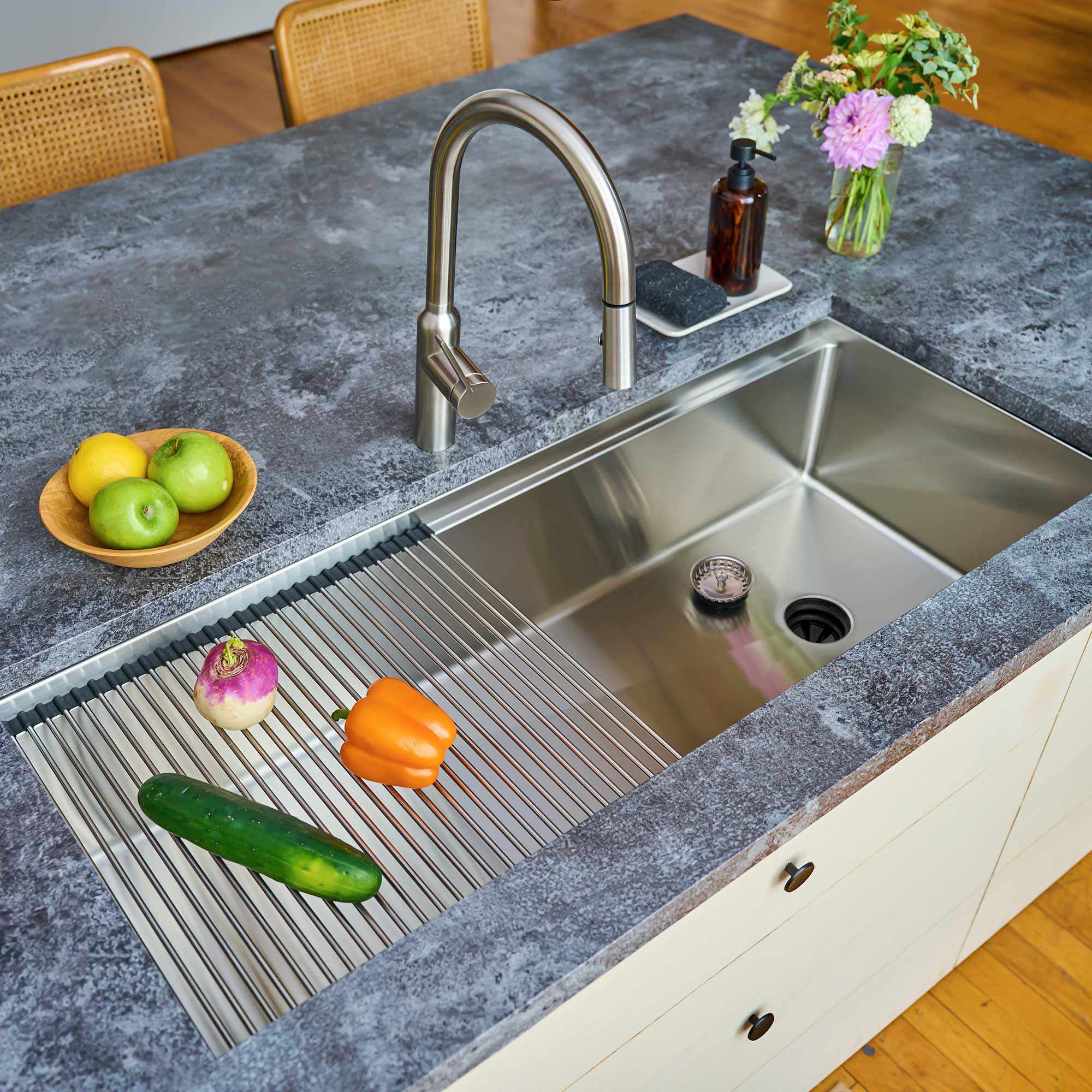 50-inch stainless steel workstation sink installed in a modern kitchen. Features a roll-up drying rack on the built-in ledge for added functionality.