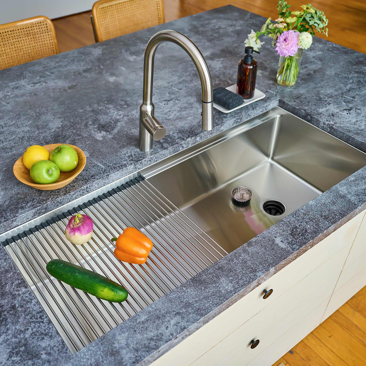 50-inch stainless steel workstation sink installed in a modern kitchen. Features a roll-up drying rack on the built-in ledge for added functionality.