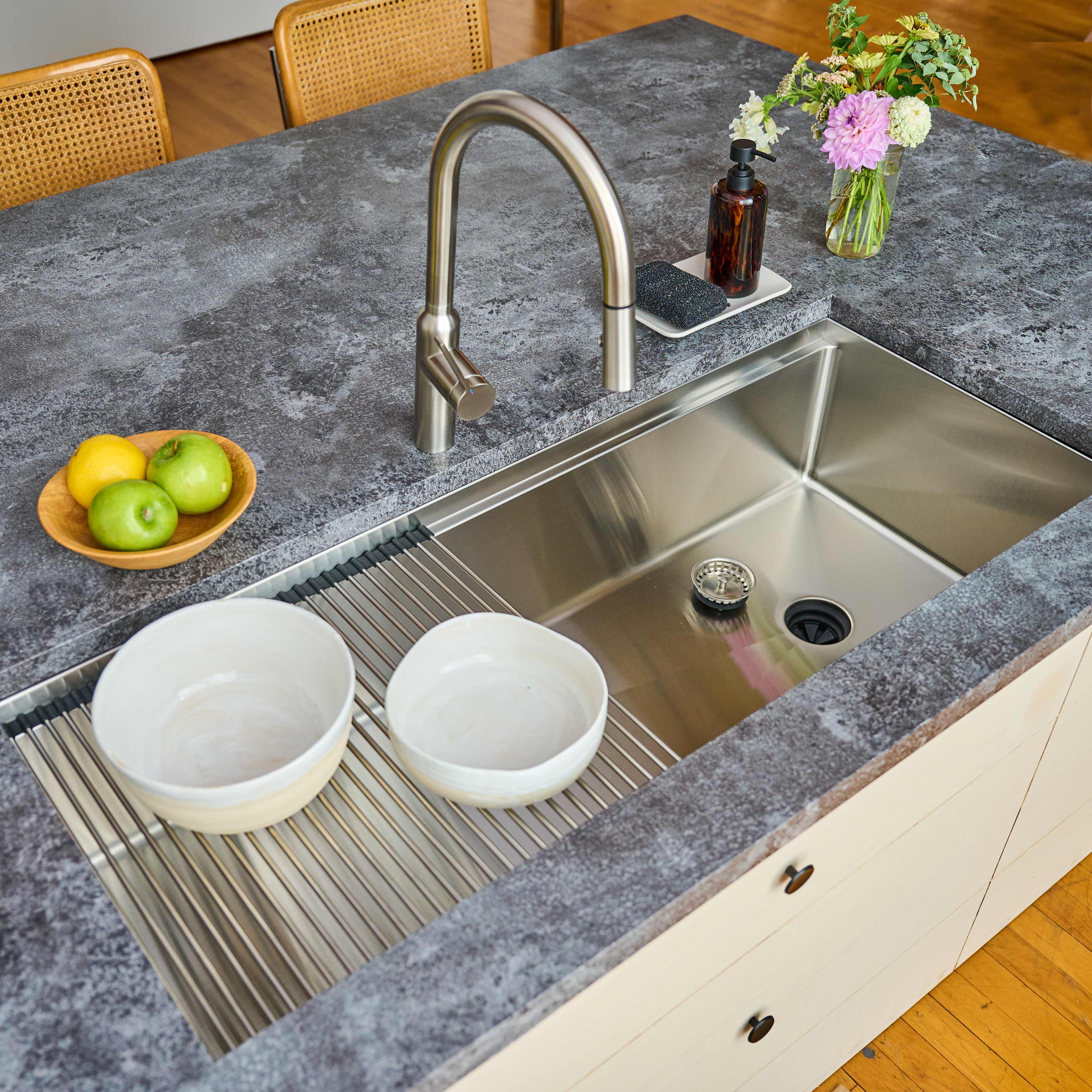 50-inch stainless steel workstation sink in a contemporary kitchen. Features a roll-up drying rack holding dishes for efficient kitchen workflow.