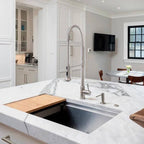 Modern kitchen with a 31-inch stainless steel workstation sink seamlessly integrated into a marble countertop, featuring a built-in ledge for accessories.