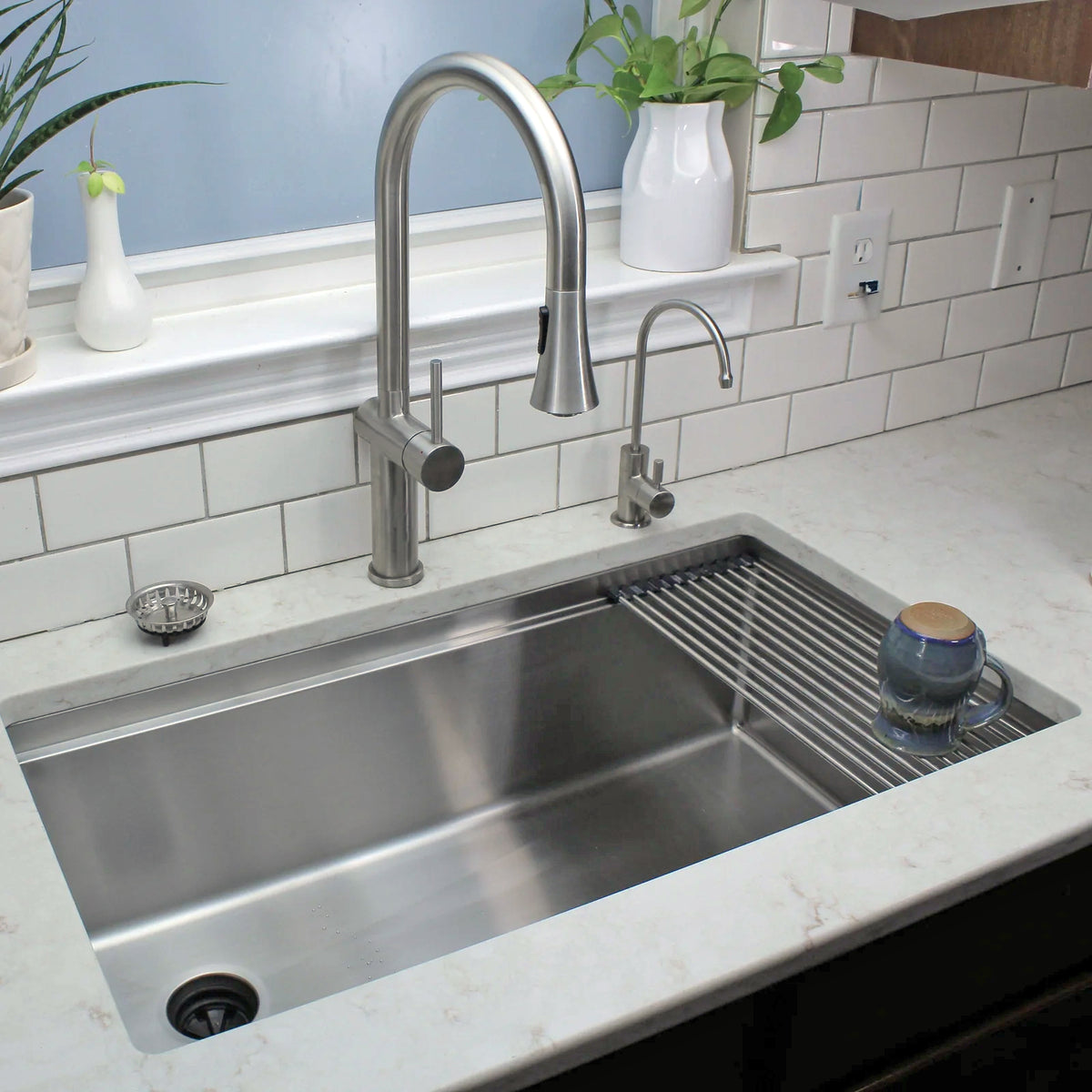 Bella stainless steel kitchen faucet installed over a large modern sink, complementing a sleek kitchen design with a tiled backsplash.