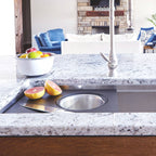 Workstation sink setup with an 18-inch black cutting board and stainless steel colander, ideal for straining and food preparation.