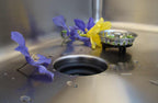 Close-up of a stainless steel sink with a Seamless Drain and Disposal Kit strainer basket, highlighting its sleek and functional design.