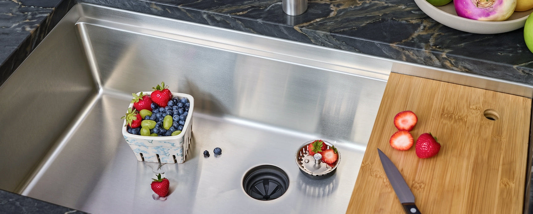 Stainless steel undermount workstation sink with feature callouts — drain, corners, ledge, and accessories