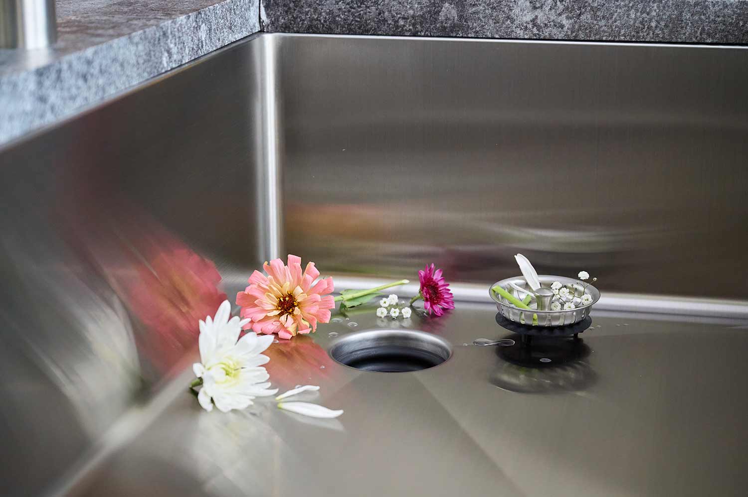 Stainless steel kitchen sink with offset corner drain and patented seamless drain feature