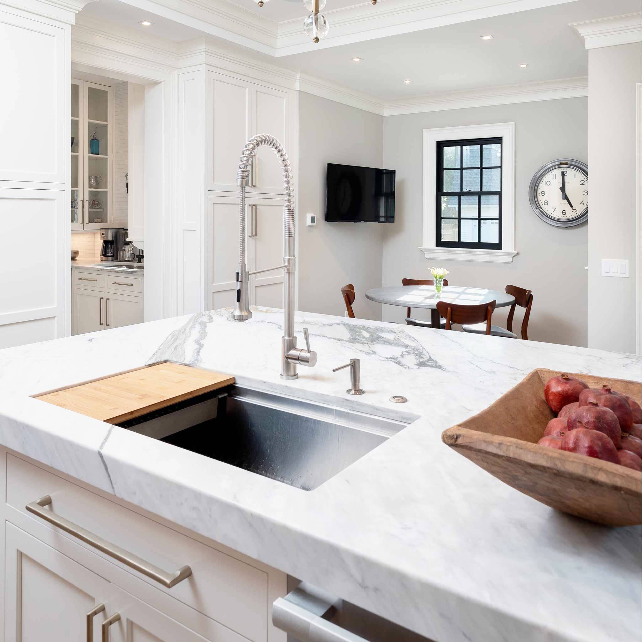 Modern kitchen with a 37-inch workstation sink integrated into a marble countertop. Features a pull-down faucet and built-in ledge for accessories.