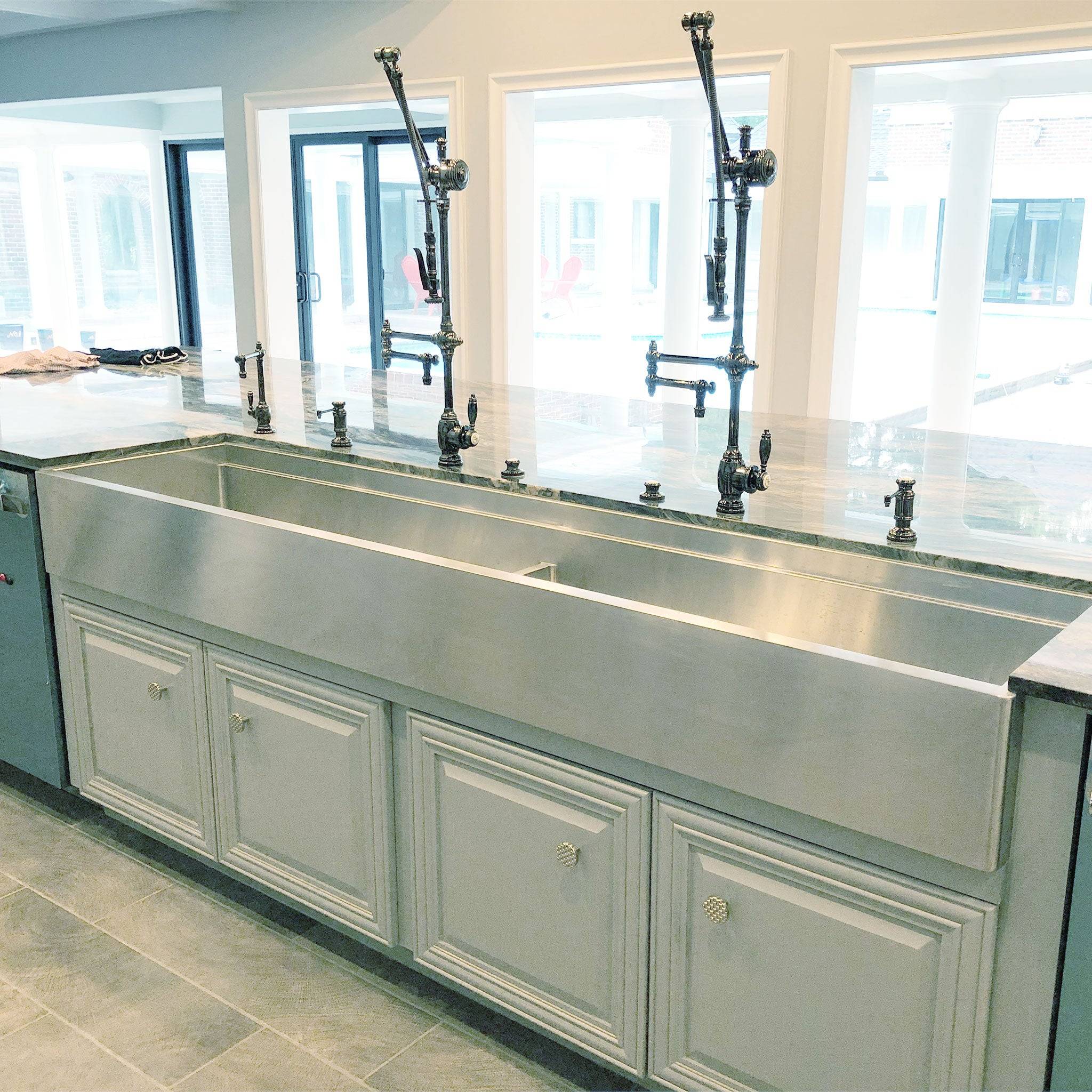 Installed 84-inch stainless steel farmhouse sink with apron front, seamlessly integrated into a modern kitchen with custom cabinetry.