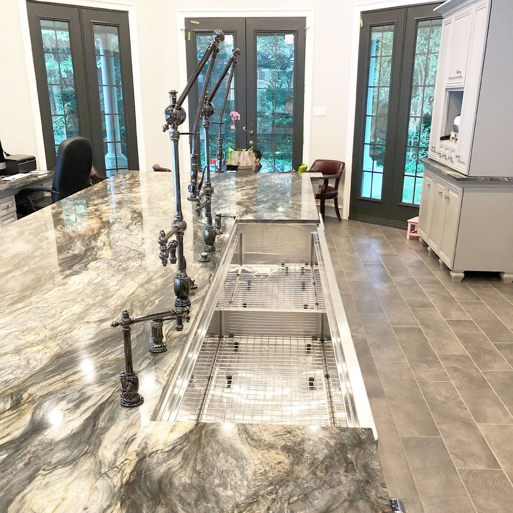 Expansive 84-inch stainless steel apron front sink installed in a luxury kitchen with marble countertops and industrial-style faucets.