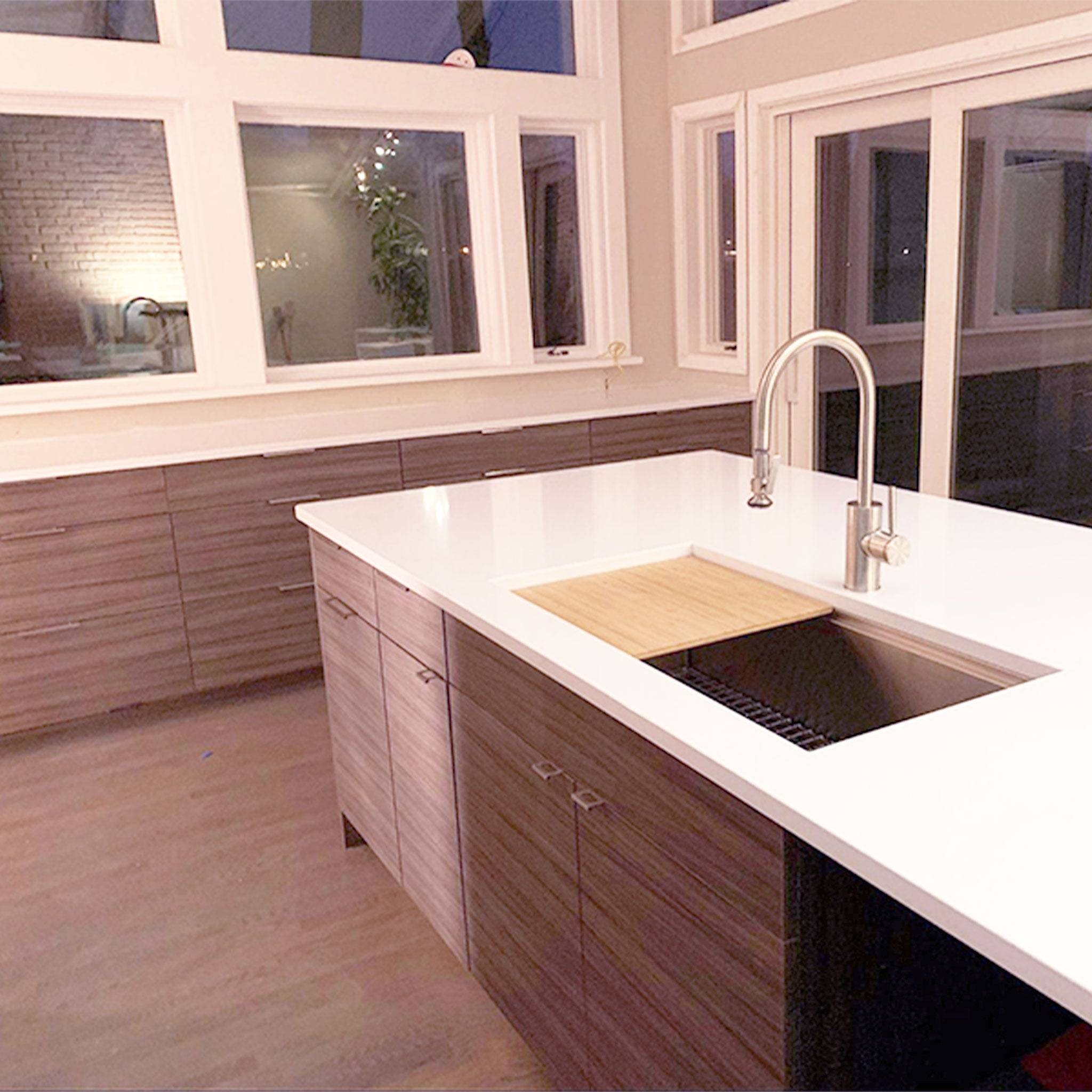 Spacious modern kitchen featuring a 37-inch workstation sink with a built-in ledge. Sleek white countertop and dark wood cabinetry enhance aesthetics.