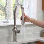 Hand pulling down the Bella stainless steel kitchen faucet’s spray head, showcasing its flexible and ergonomic design for easy rinsing.